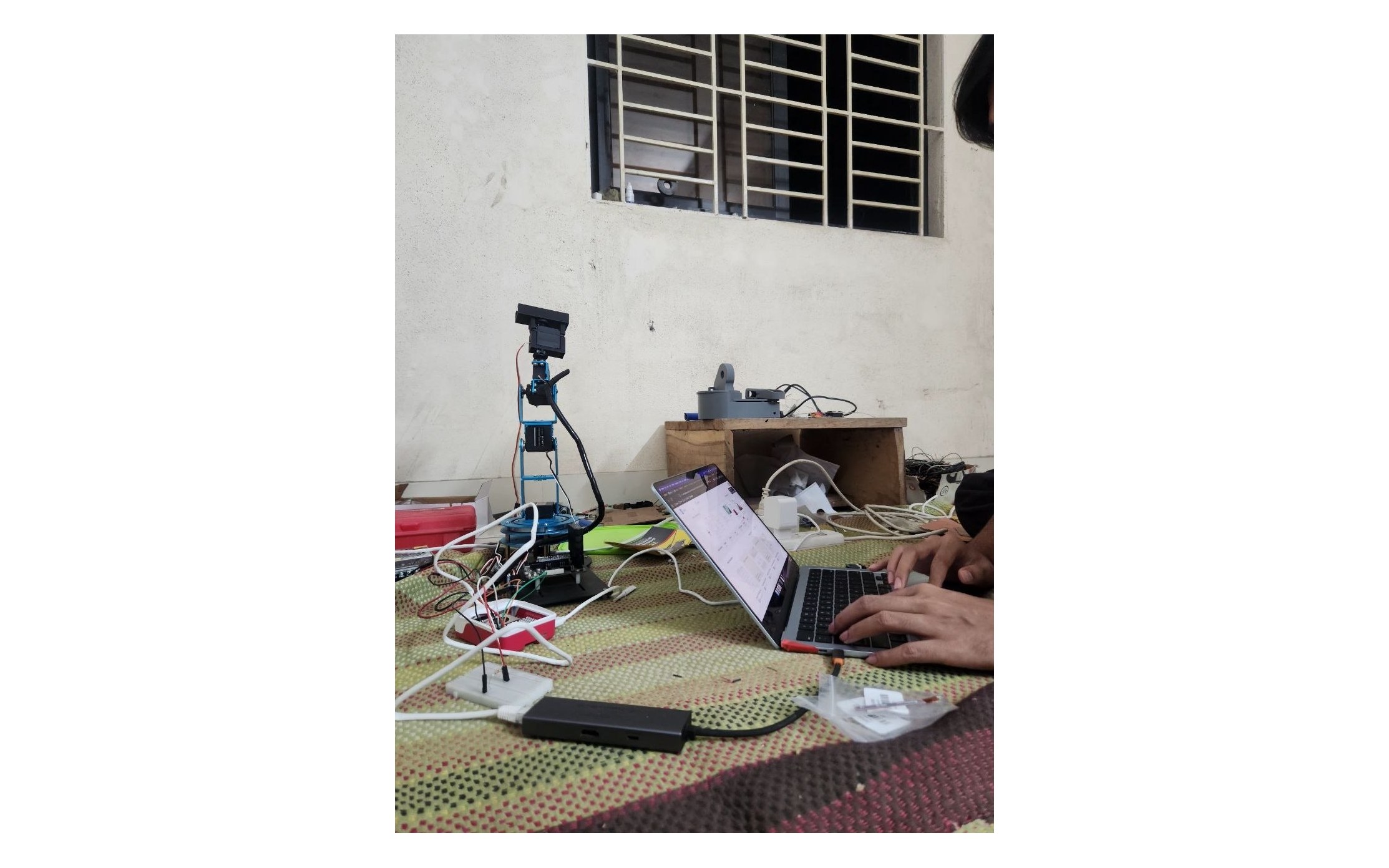 Prototype arm on the bench beside a laptop running the control software