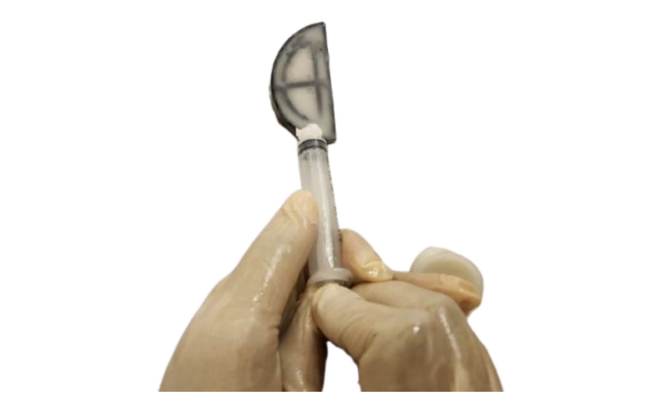 Gloved hand holding a freshly mixed silicone rubber sample on a stirring stick