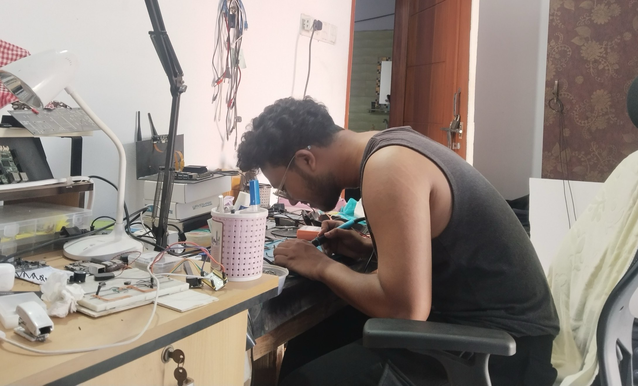 Engineer soldering the sensor harness at a cluttered electronics bench